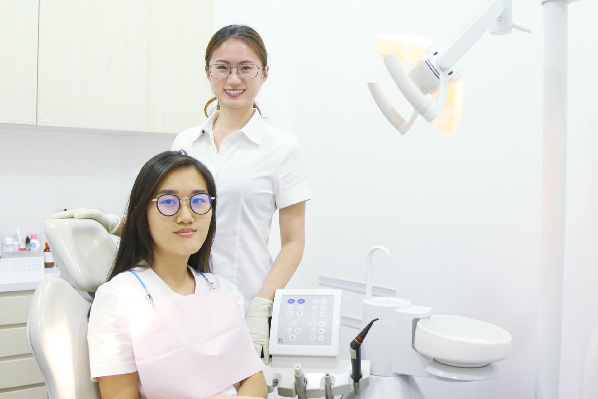 Dr Li Kexin dentist standing beside her patient, patient is seated in the dental chair