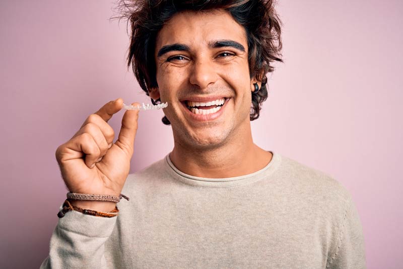 happy indian man posing with his Invisalign clear aligners while doing Invisalign treatment in singapore