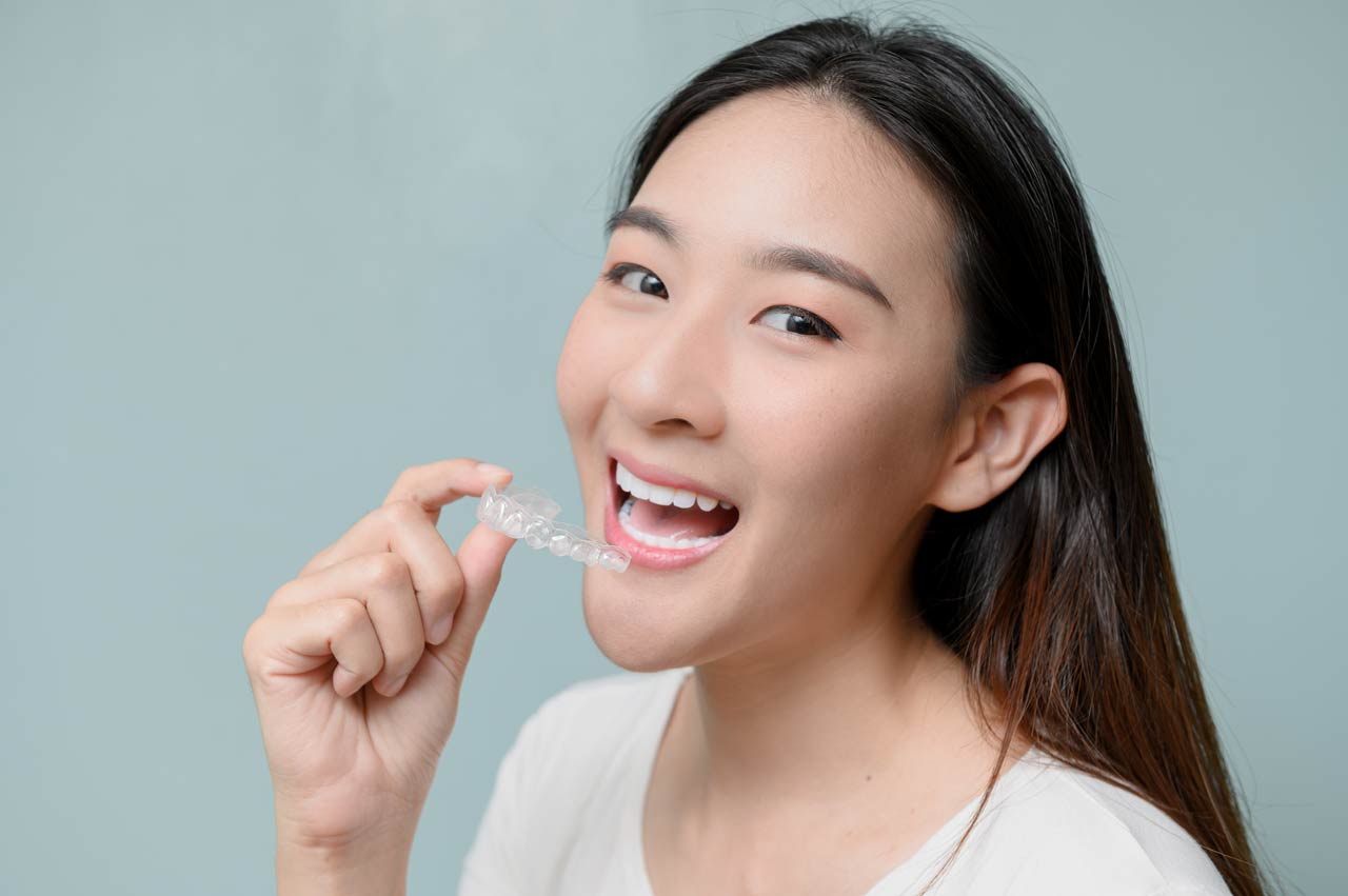 Happy asian lady posing with her Invisalign aligners