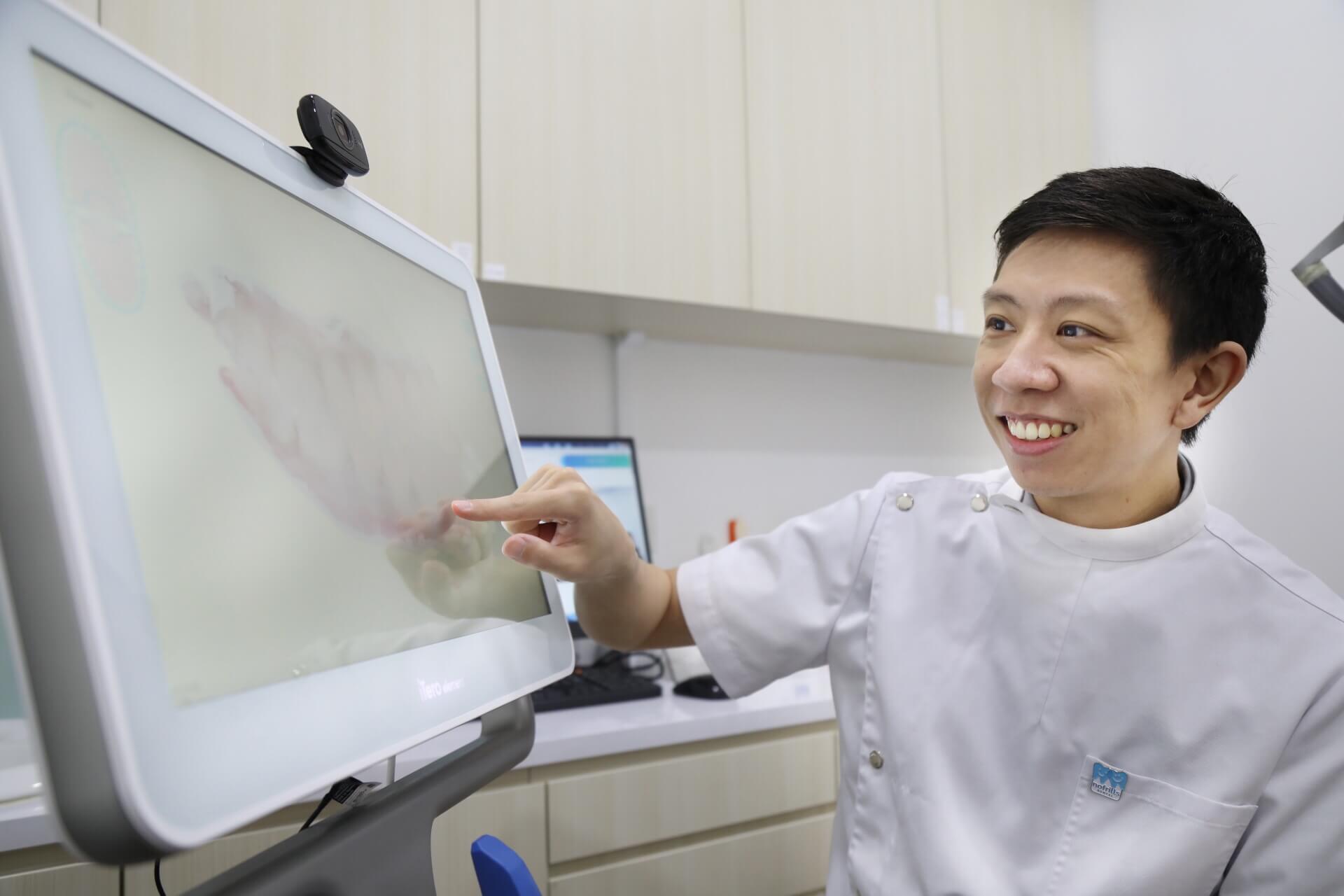 Dr Li Kexin dentist standing beside her patient, patient is seated in the dental chair