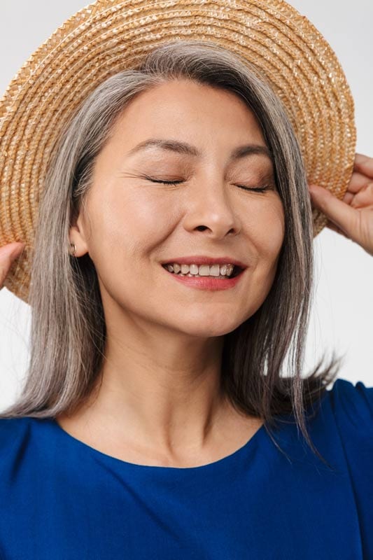 lady with dental implants smiling while writing on her red booklet