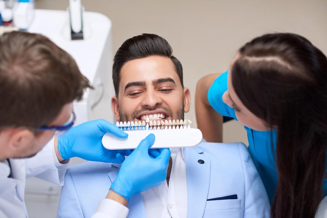 young man getting his teeth checked for the right tooth shade before getting dental veneers