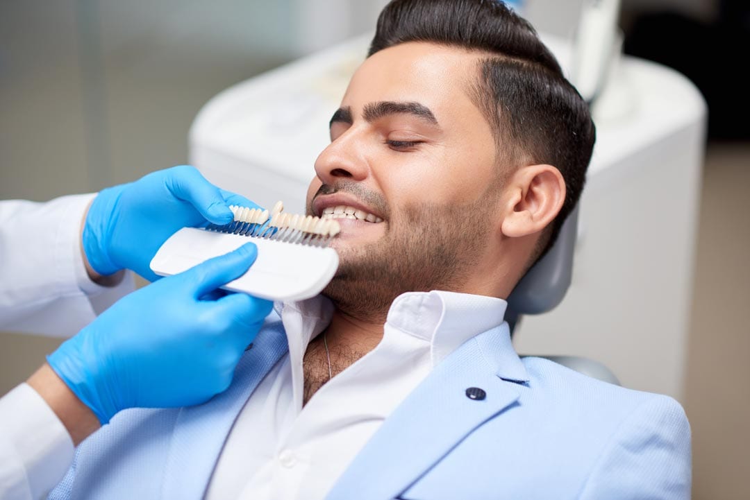 young man getting his teeth checked for the right tooth shade before getting dental veneers