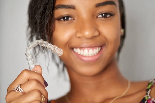 Happy teen ager holding onto Invisalign clear aligners