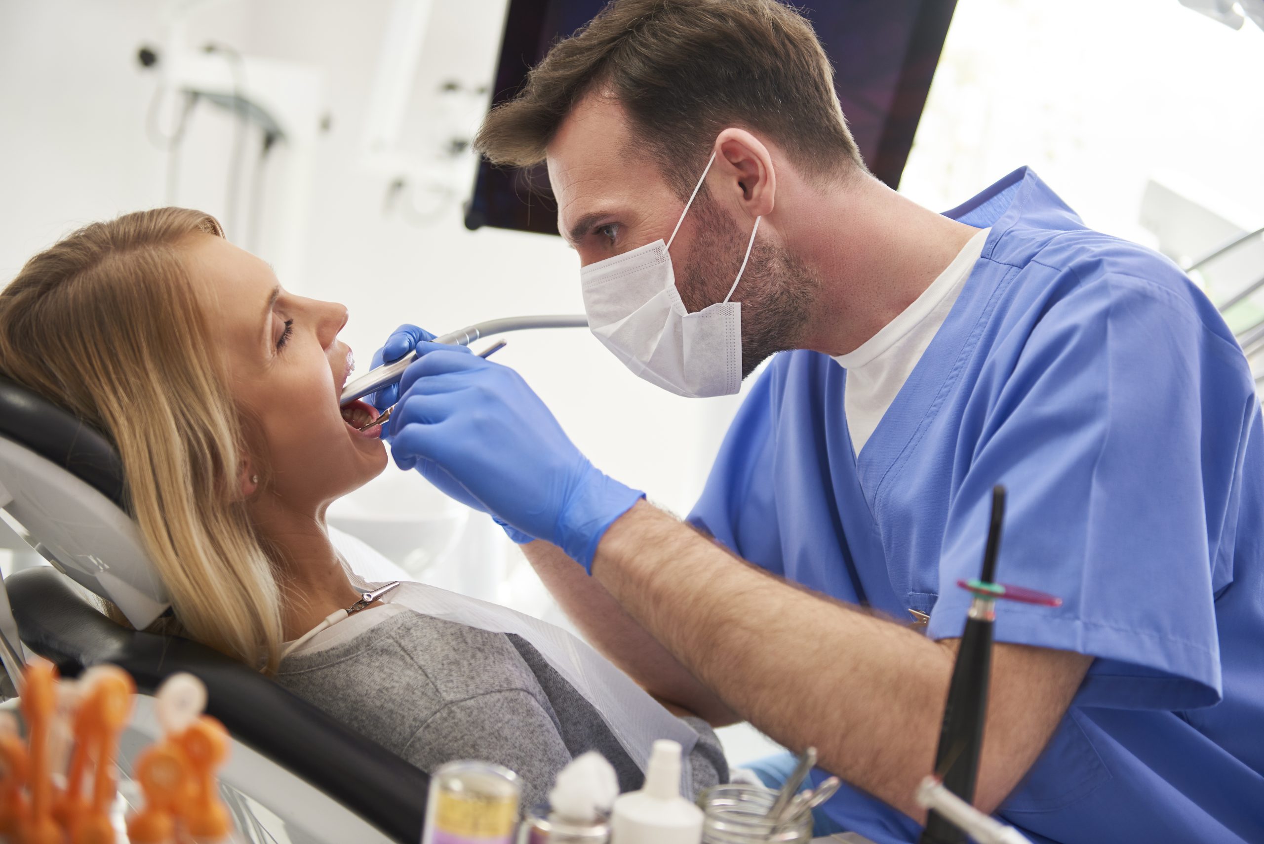 Focused stomatologist using dental drill and dental mirror dental visit