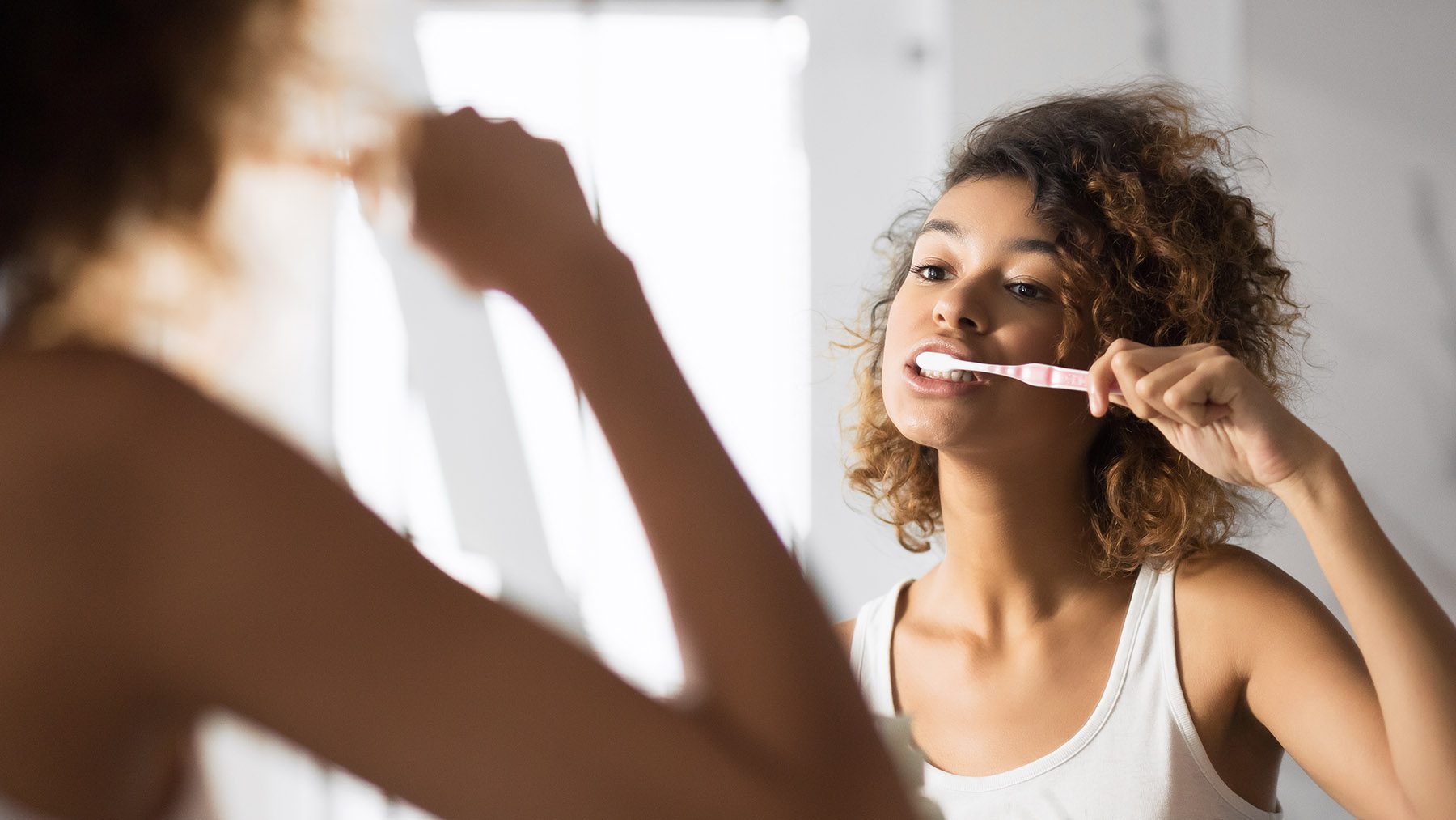 woman brushing her teeth infront of mirror woman brushing her teeth infront of mirror