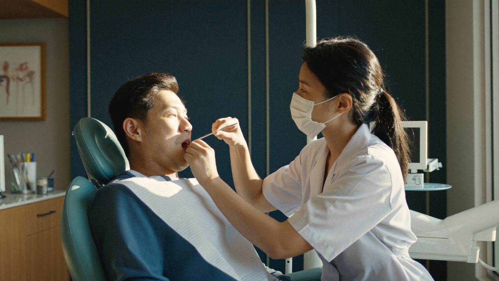 Dentist examining a patient's mouth for early signs of oral cancer during a routine checkup in Singapore