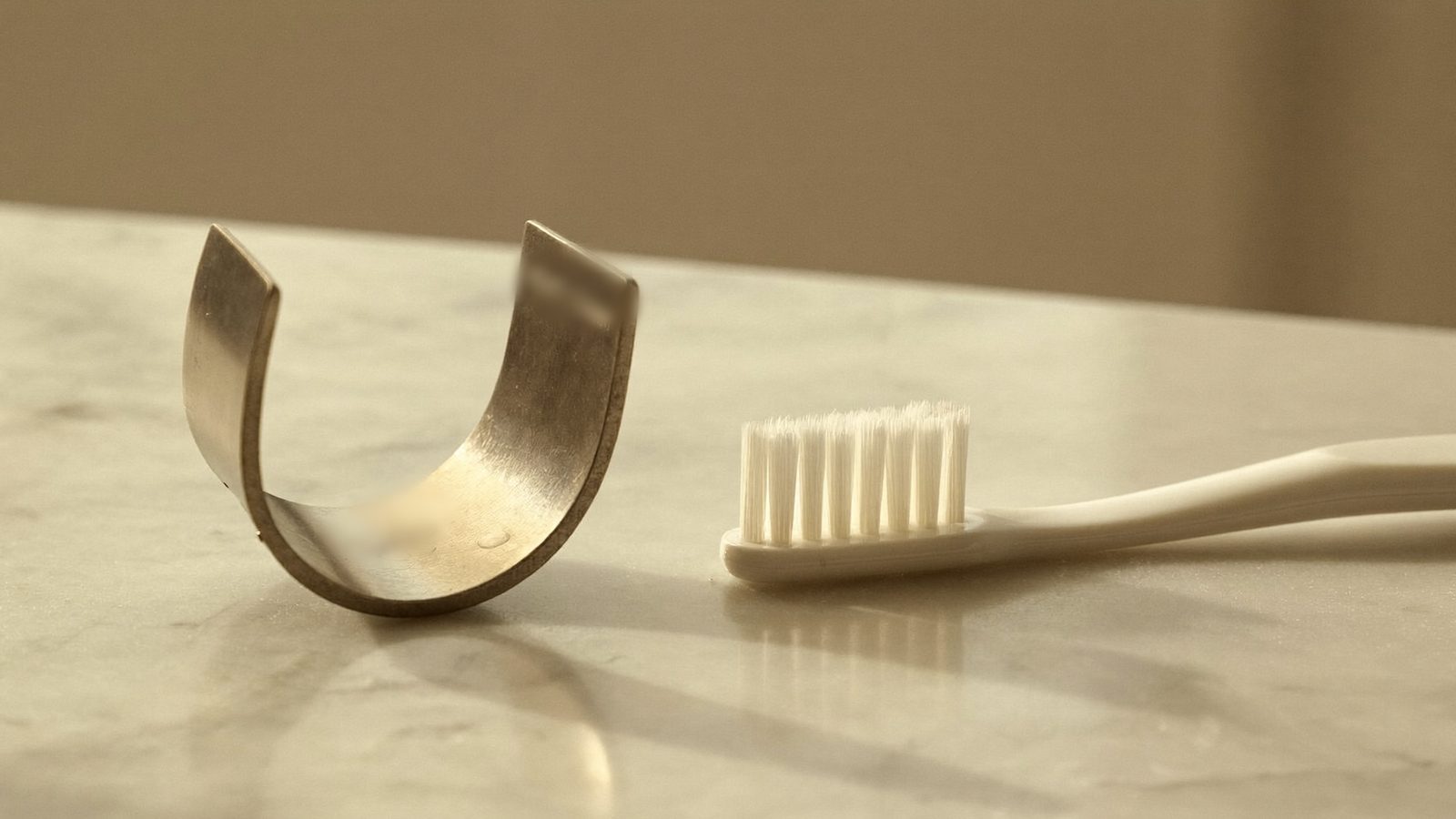 Tongue scraper and toothbrush on a bathroom counter, the two tools that remove the cause of bad breath