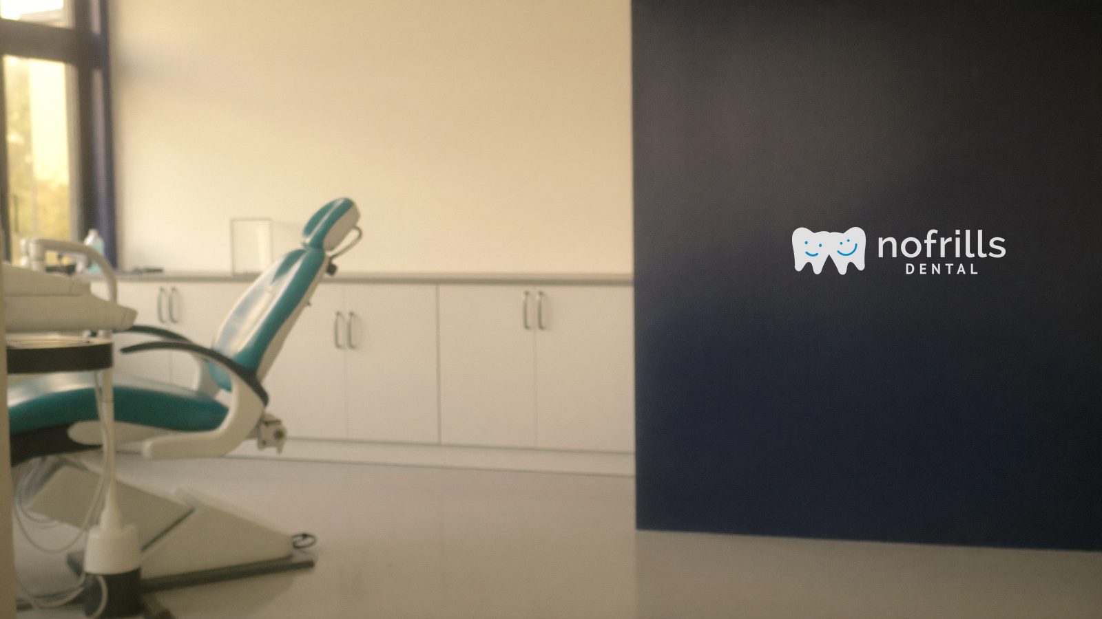 Treatment room at a NoFrills Dental clinic in Singapore with the clinic logo on the navy wall