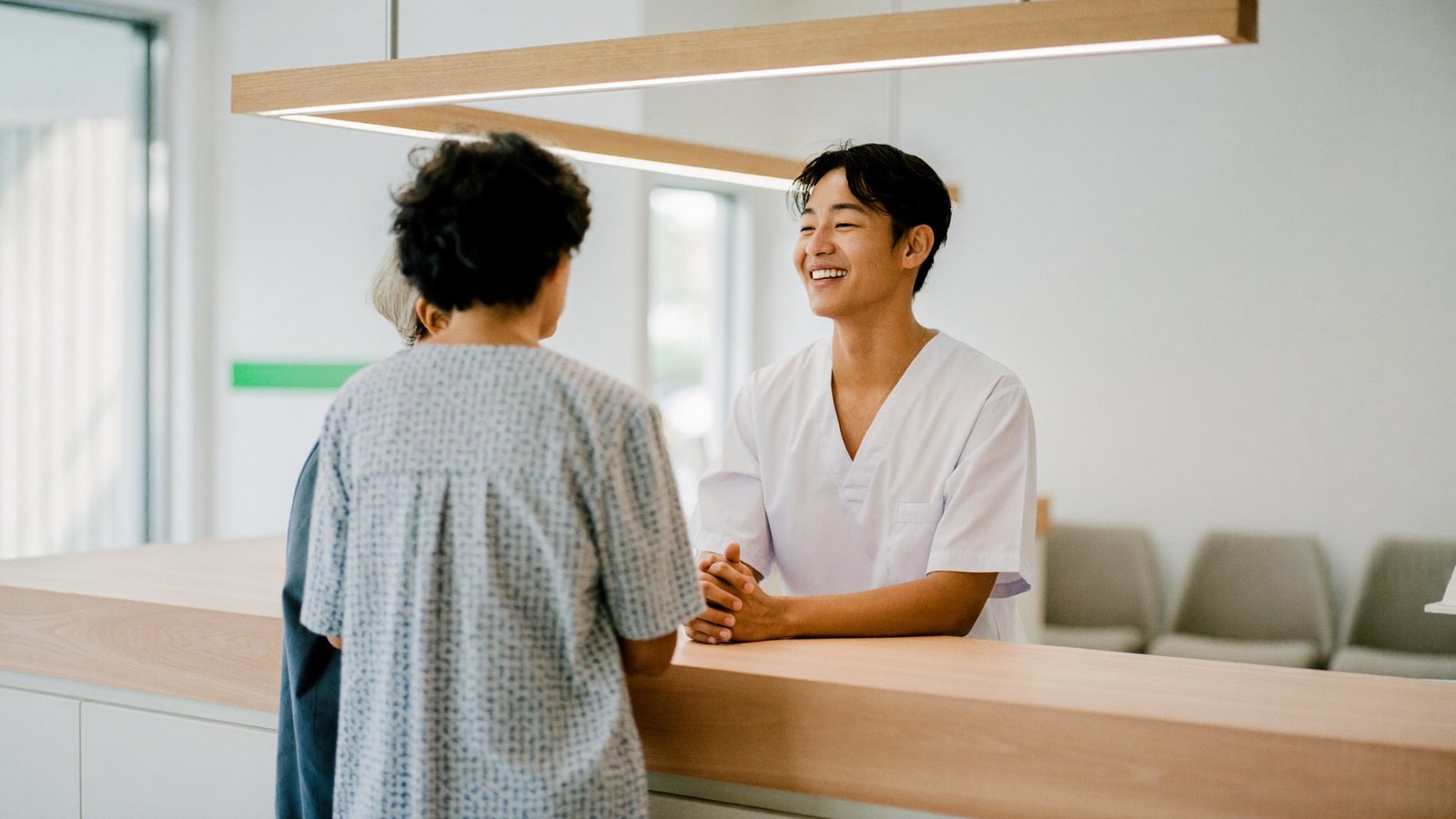 Patients speaking with a receptionist about dental fees and CHAS subsidies at a Singapore dental clinic counter