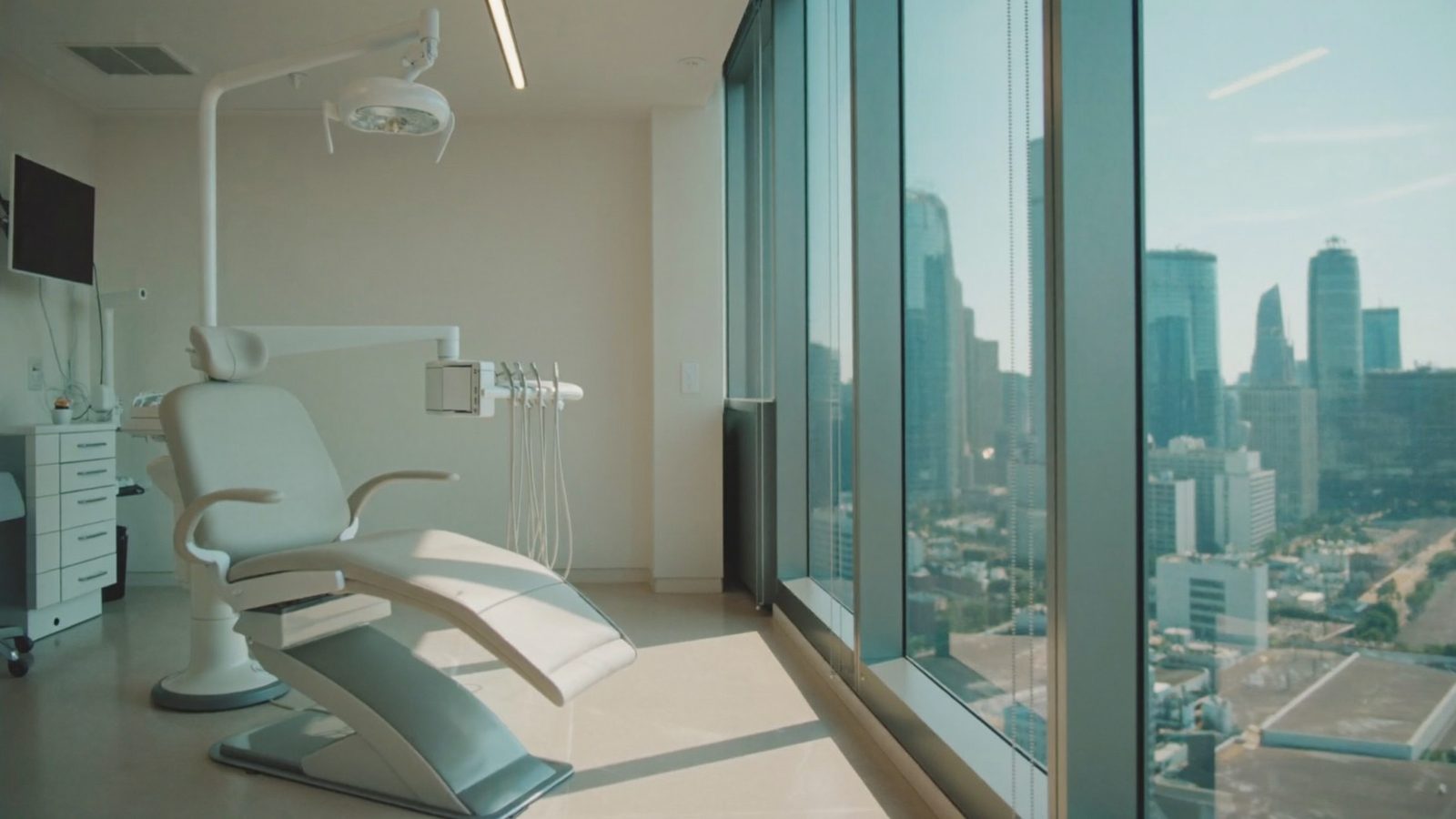 Dental treatment room high in an office tower with city towers visible through the window