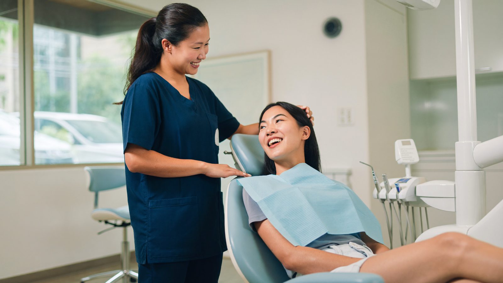 A dentist speaking calmly with a patient holding their jaw in a bright modern Singapore dental surgery