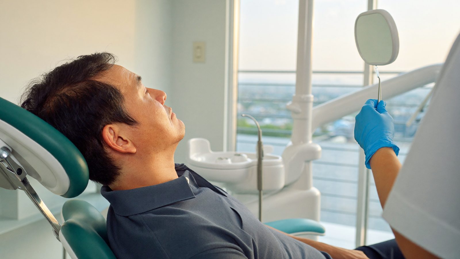 Dentist examining an older Singaporean man's gums during a routine dental check-up