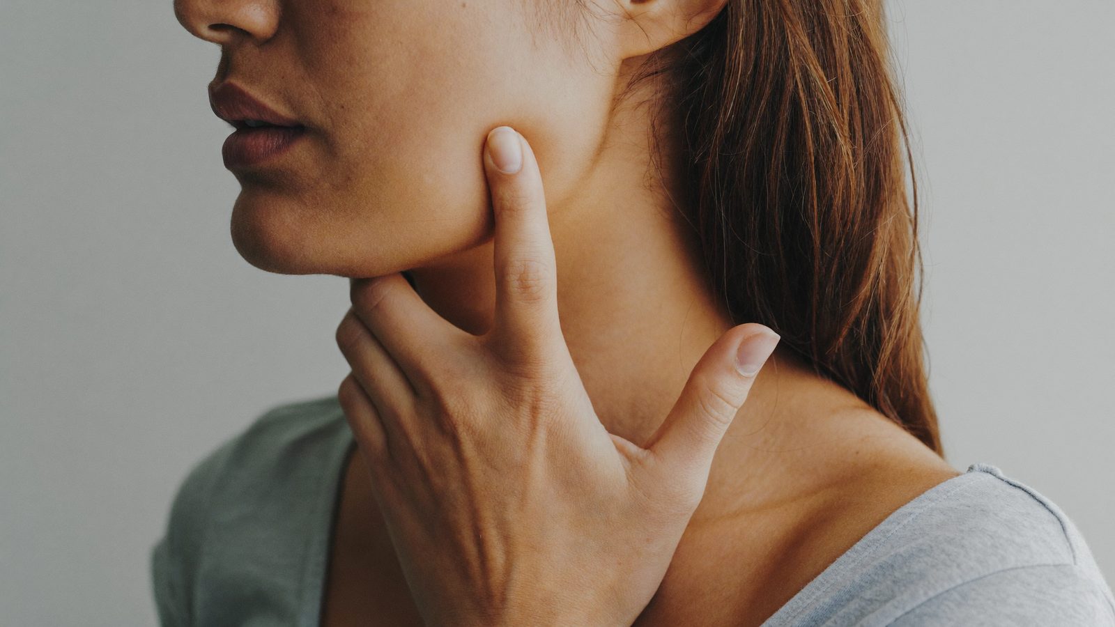 Woman pressing her fingers against a painful jaw joint in front of her ear